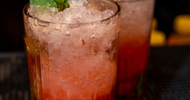 Three colorful summer cocktails with mint, lime, and fruit garnishes on a marble surface — neon bar vibe